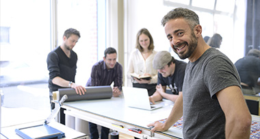 group of people collaborating in a creative workspace smiling and engaged in a project involving design and planning for six innovative ideas