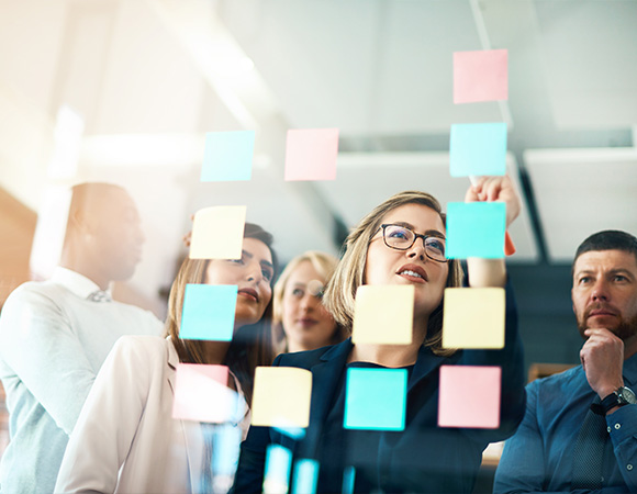 group of professionals collaborating with colorful sticky notes in a modern office environment discussing ideas for five strategic goals