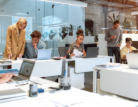 people collaborating in a modern office environment with laptops and paperwork emphasizing teamwork and productivity featuring thirteen key elements of teamwork