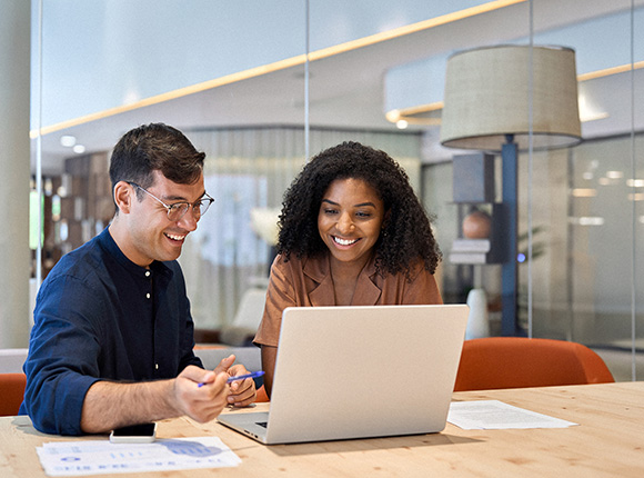 two colleagues discussing ideas while working on a laptop in a modern office setting with a warm atmosphere