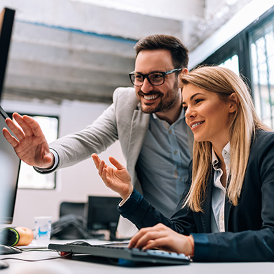 two professionals collaborating in an office discussing project details while looking at a computer screen with a focus on teamwork and productivity 6 strategies for success