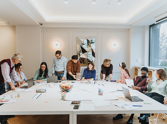 diverse group of people collaborating in a modern office setting with laptops and documents during a creative meeting about four innovative ideas