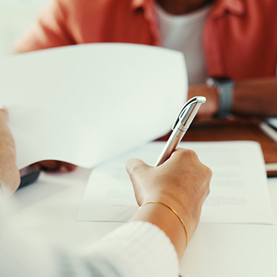 person writing on a document with a pen while another individual is holding papers in a meeting about contracts and agreements for three important points
