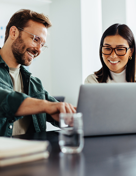 two colleagues collaborating on a laptop with friendly expressions in a modern office setting showcasing success strategies for the number 7