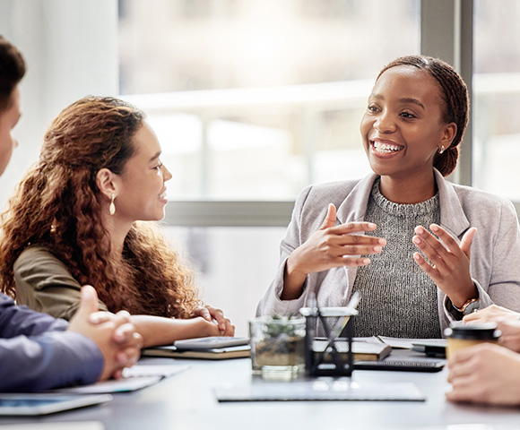 four professionals engaged in discussion at a meeting table with one woman speaking animatedly three team members listening attentively