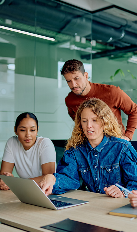 three people collaborating in a modern office setting reviewing a laptop screen showcasing five key ideas or features