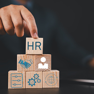 hand placing wooden blocks labeled with HR on a table symbolizing human resources and team building strategies for 14 effective management techniques