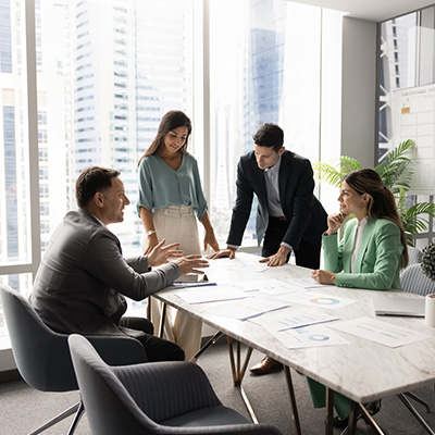 business meeting with four professionals discussing documents and charts in a modern office context brainstorming strategies focused on twelve key objectives