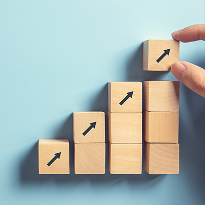 wooden blocks arranged in ascending order with upward arrows indicating progress and growth in a strategy to reach 7 goals