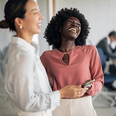 two women laughing together in an office setting with the number 13 signifying joy and connection